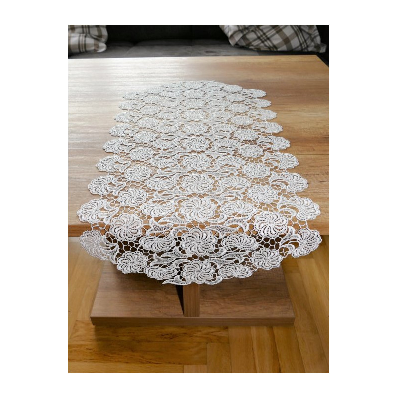 Ovaler Tischläufer aus cremeweißer Plauener Spitze mit floraler Stickerei flach auf Holz-Couchtisch ausgelegt.