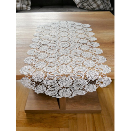 Ovaler Tischläufer aus cremeweißer Plauener Spitze mit floraler Stickerei flach auf Holz-Couchtisch ausgelegt.