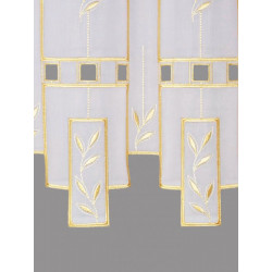 Nahaufnahme von filigraner Plauener Spitze in Goldgelb und Weiß mit floralem Muster auf halbtransparentem Stoff.