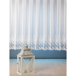 Weiße Kurzgardine aus Plauener Spitze vor blauem Grund mit Deko-Laterne. Edle Heimtextilien für gemütliches Wohnen.