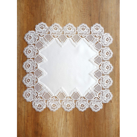 Quadratisches Tischset aus cremeweißer Plauener Spitze mit prachtvollem Rosenrand flach auf Holzmöbel.