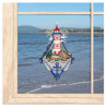 Gesticktes Fensterbild mit maritimem rot-weißen Leuchtturm im sonnigen Strand-Ambiente am Fenster.