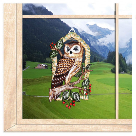 Gesticktes Fensterbild mit Waldkauz auf einem Ast inmitten einer stimmungsvollen, herbstlichen Waldkulisse.