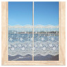 Maritime Scheibengardine aus Plauener Spitze mit blauen Fischen am Fenster mit Meerblick.