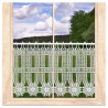 Transparente weiße Scheibengardine aus Plauener Spitze im Fenster mit Blick auf grüne Natur.