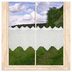 Weiße Kurzgardine aus Plauener Spitze mit detailreicher Stickerei am Fenster im Zimmer mit Blick ins Grüne als Heimtextilien.