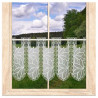 Transparente Scheibengardine aus Plauener Spitze mit Blumenmuster am Holzfenster vor Naturkulisse.