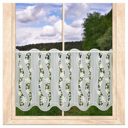 Transparente Scheibengardine aus naturweißer Plauener Spitze mit Blumenmuster am Holzfenster vor Naturkulisse.