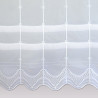 Detail einer weißen Plauener Spitze Raffgardine mit bogenförmigem Abschluss und Lochstickerei-Mustern.
