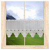 Halbtransparente Scheibengardine mit beiger Stickerei am Holzfenster im gemütlichen Raumambiente.