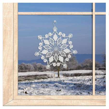 Filigrane Schneeflocke aus weißer Plauener Spitze als Winter-Fensterbild am Fenster.