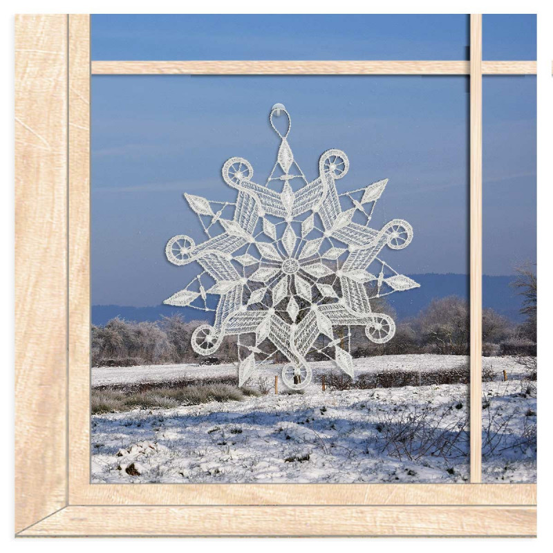 Verzierte Schneeflocke aus weißer Plauener Spitze als romantisches Fensterbild im winterlichen Ambiente.