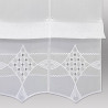 Nahaufnahme weißer Plauener Spitze mit Rautenmuster, Stickereien und Wellensaum für exklusive Heimtextilien.