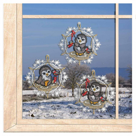 Drei filigrane Pinguin-Fensterbilder aus Spitze im winterlich dekorierten Wohnzimmer-Ambiente am Fenster.