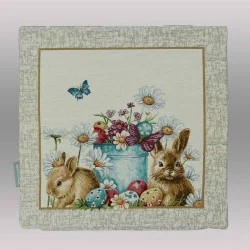 Am unteren Rand dieser Kissenhülle sind liebevoll verzierte Ostereier in verschiedenen Farben (Blau, Rot, Gelb) im grünen Gras versteckt.

Belebte Natur: Zwei Schmetterlinge – einer in leuchtendem Blau und einer in gedecktem Violett – verleihen der Szenerie zusätzliche Dynamik.