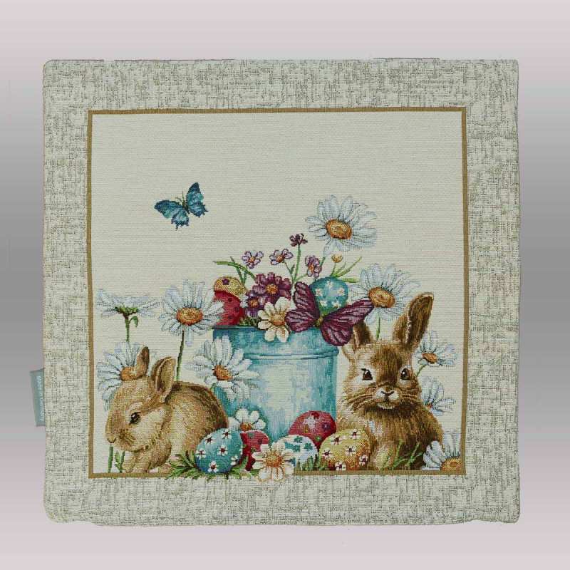 Am unteren Rand dieser Kissenhülle sind liebevoll verzierte Ostereier in verschiedenen Farben (Blau, Rot, Gelb) im grünen Gras versteckt.

Belebte Natur: Zwei Schmetterlinge – einer in leuchtendem Blau und einer in gedecktem Violett – verleihen der Szenerie zusätzliche Dynamik.