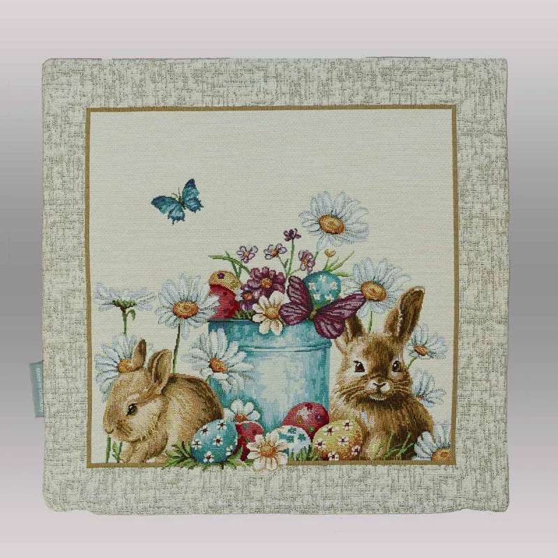 Am unteren Rand dieser Kissenhülle sind liebevoll verzierte Ostereier in verschiedenen Farben (Blau, Rot, Gelb) im grünen Gras versteckt.

Belebte Natur: Zwei Schmetterlinge – einer in leuchtendem Blau und einer in gedecktem Violett – verleihen der Szenerie zusätzliche Dynamik.