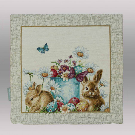 Am unteren Rand dieser Kissenhülle sind liebevoll verzierte Ostereier in verschiedenen Farben (Blau, Rot, Gelb) im grünen Gras versteckt.

Belebte Natur: Zwei Schmetterlinge – einer in leuchtendem Blau und einer in gedecktem Violett – verleihen der Szenerie zusätzliche Dynamik.