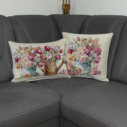 Verleihen Sie Ihrem Wohnzimmer eine frische, lebendige Atmosphäre mit unseren beiden Zierkissen "Frühling". Das detailreiche Motiv zeigt ein prachtvolles Arrangement aus Tulpen, Narzissen und weiteren Frühlingsblühern in einem nostalgischen Eimer oder einer Gießkanne., hier plaziert auf einem grauen Sofa.