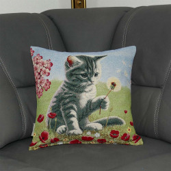 Bringen Sie mit unserem Kissenbezug "Mieze" den Charme verspielter Eleganz in Ihr Wohnzimmer. Das detailreiche Motiv zeigt eine neugierige Katze (Mieze) auf einer Blumenwiese, die behutsam nach einer Pusteblume greift.Hier ist das Kissen auf einen grauen Sofa platziert.