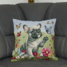 Das Kissen "Kleine Bulldogge" platziert auf einem graunen Sofa.. Das detailverliebte Motiv zeigt eine verspielte französische Bulldogge auf einer bunten Blumenwiese, umgeben von tanzenden Schmetterlingen.