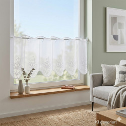 Die Kurzgardine Alegra mit Blütenstickerei in weiß-silber-taupe  in 30 cm Höhe wurde an ein sonnendurchflutetes Wohnzimmerfenster dekoriert.