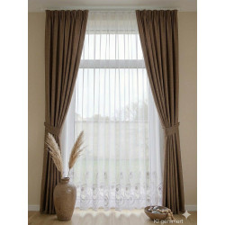 Raumaufnahme: Weißer Stickerei-Store kombiniert mit braunen Übergardinen im Landhausstil für gemütliche Wohnräume.