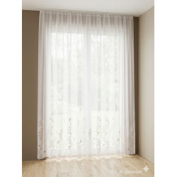 Weiße, halbtransparente Store-Gardine mit floraler Plauener Spitze am Saum vor hellem Fenster im modernen Ambiente.