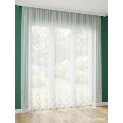 Halbtransparente weiße Store-Gardine Sancia mit geschwungener Stickerei am Abschluss vor einem großen Fenster.