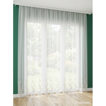 Halbtransparente weiße Store-Gardine Sancia mit geschwungener Stickerei am Abschluss vor einem großen Fenster.