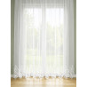 Halbtransparente Stickereigardine aus Plauener Spitze, weißes Wellendesign am Saum vor hellem Fenster, Sichtschutz.