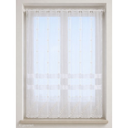 Halbtransparente Raffgardine in Weiß mit elegant gestickten Rauten-Motiven und wellenförmigem Bogenabschluss vor hellem Raum.