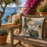 Mediterranes Gobelin-Dekokissen mit Olivenschalen-Motiv auf einer Holzbank auf einer sonnigen Steinterrasse.