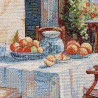 Detail eines gewebten Gobelin-Dekokissens mit mediterranem Stillleben aus Früchten und Glaskrug in Nahaufnahme.