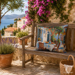 Mediterranes Gobelin-Dekokissen mit Orangenbaum-Motiv auf einer Holzbank auf einer Terasse mit Meerblick im Hintergrund.