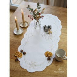 Festlicher Tischläufer mit goldener Stickerei, dekoriert mit Tannenzapfen und Kerzen auf Holztisch im Esszimmer.