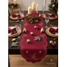 Tischläufer mit goldener Stickerei auf weihnachtlich dekoriertem Esstisch mit Kerzen und Geschirr.