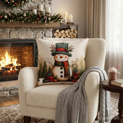 Gobelin-Dekokissen mit Schneemann im modernen Wohnzimmer auf grauem Sessel neben einer gemusterten Kuscheldecke.
