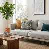 Gemütliches Wohnzimmer mit grauem Sofa, stilvollem Farn-Dekokissen und harmonischen Heimtextilien in Naturfarben.