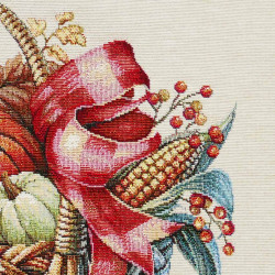 Detailaufnahme von gewebtem Gobelin-Stoff mit Herbstmotiv aus Erntekorb, Mais und roter Schleife.