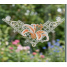 Plauener Spitze Fensterbild mit orangefarbener Lilie, per Saugnapf am Fenster befestigt vor Gartenkulisse.