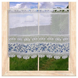 Am Fenster dekoriert: Scheibengardine Lisann aus weißer Plauener Spitze mit blauem Floralmuster.