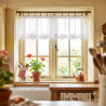 Weiße Kurzgardine aus Plauener Spitze mit elegantem Lochmuster an einer Holzstange am Fenster in gemütlicher Küche.