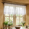 Weiße Bistro-Gardine aus Plauener Spitze am Küchenfenster mit Holzdeko, Kräutertöpfen und Frühlingsblumen.
