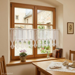 Transparente Scheibengardine aus naturweißer Plauener Spitze am Holzfenster im gemütlichen Esszimmer.