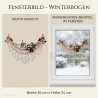 Winterliches Heimtextilien-Fensterbild als Bogen mit blauen Vögeln, schneebedecktem Dorf, Eiszapfen und Schneeflocken im Fenster.