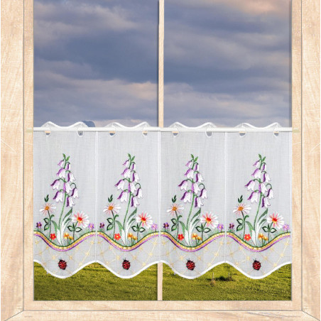 Kurzgardine in Weiß mit Glockenblumen-Stickerei und Marienkäfern als Heimtextilien im Fenster.