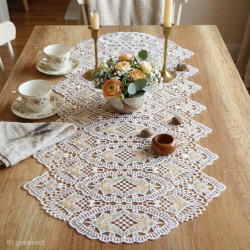 Cremeweißer Spitzen-Tischläufer auf Holztisch mit Blumenvase arrangiert für ein stilvolles Esszimmer-Ambiente.